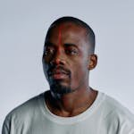 A portrait of a man in a white T-shirt with a red scanning line on his face, depicting advanced technology.